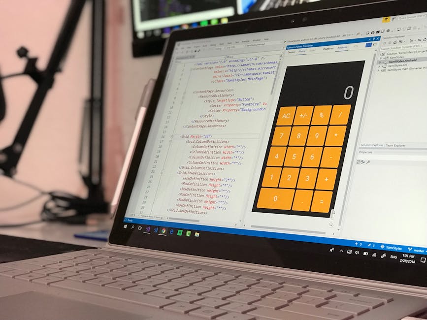 A close-up view of a laptop computer with a silver body and white keyboard, displaying a coding editor on the screen alongside a large, orange calculator interface. The coding editor shows lines of HT